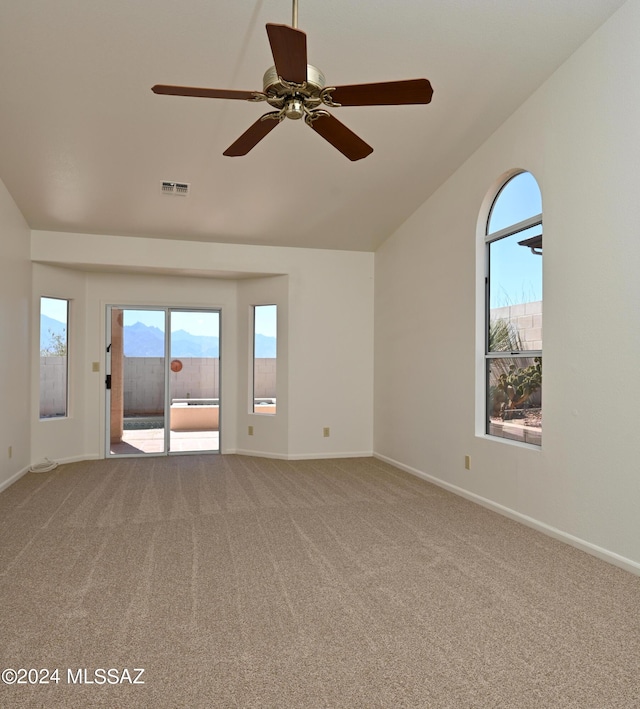 carpeted spare room featuring baseboards, vaulted ceiling, a wealth of natural light, and visible vents