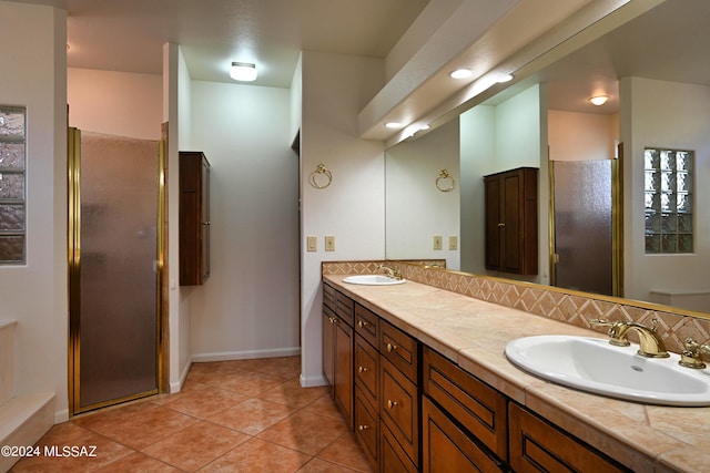 full bath featuring double vanity, tile patterned flooring, a shower stall, a sink, and baseboards