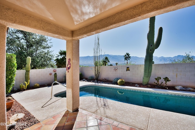 view of pool with a fenced backyard, a fenced in pool, a mountain view, and a patio area