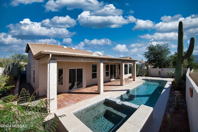 back of house with a patio, a fenced backyard, stucco siding, and a pool with connected hot tub