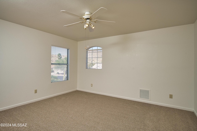 spare room featuring carpet floors, a ceiling fan, baseboards, and visible vents