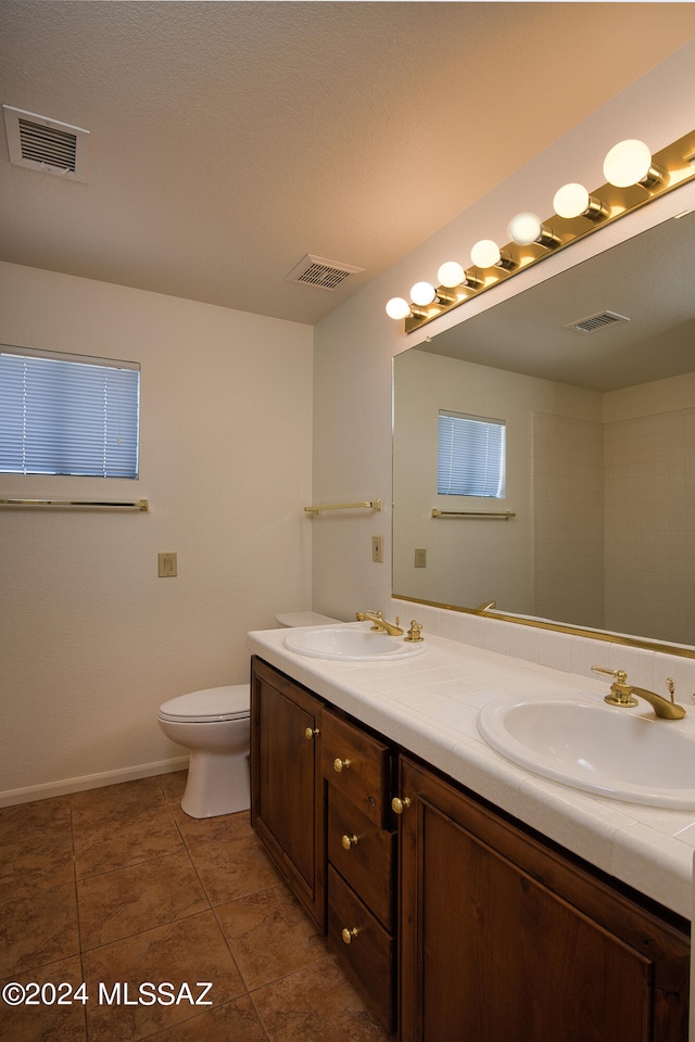 bathroom with a textured ceiling, tile patterned flooring, vanity, and toilet