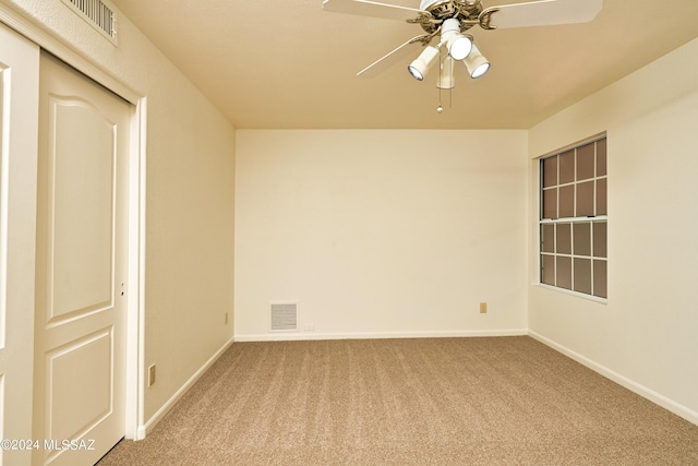 carpeted spare room with visible vents, a ceiling fan, and baseboards