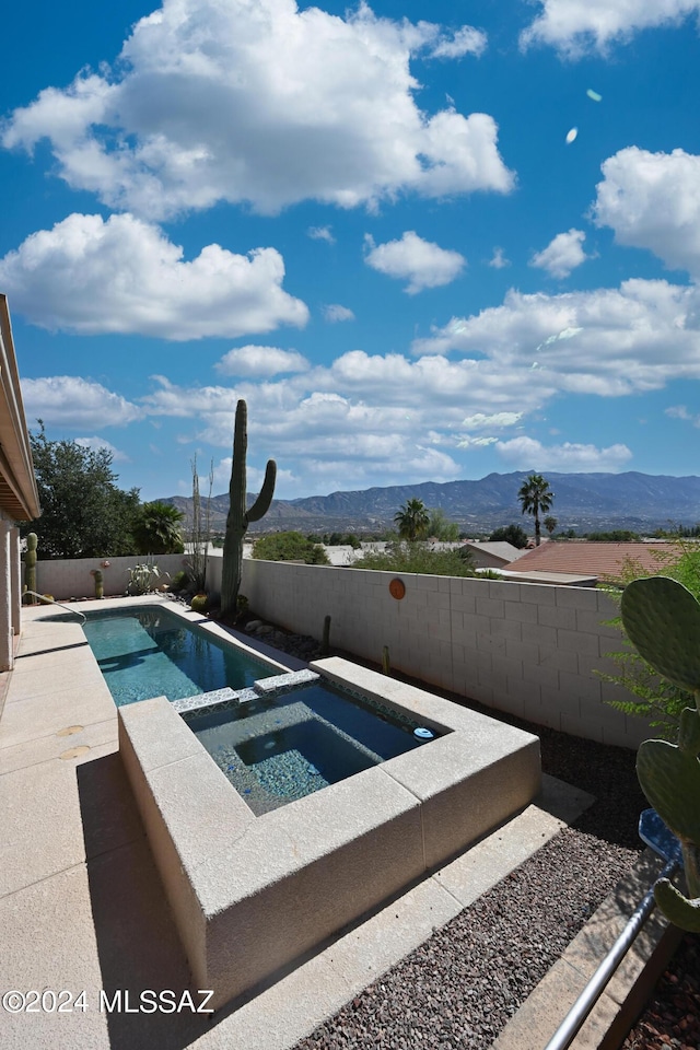view of pool featuring a fenced in pool, a mountain view, an in ground hot tub, and a fenced backyard