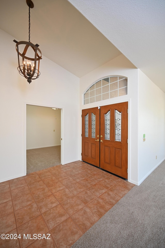 entrance foyer with carpet floors, an inviting chandelier, and high vaulted ceiling