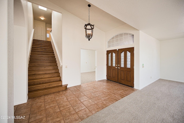 tiled foyer with carpet floors, stairs, baseboards, and a notable chandelier