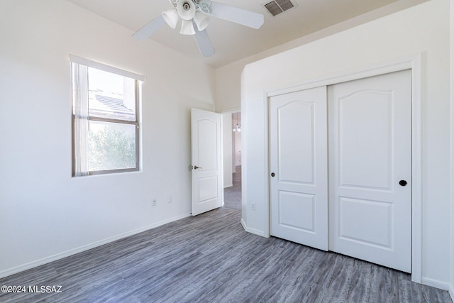 unfurnished bedroom featuring dark hardwood / wood-style flooring, ceiling fan, and a closet