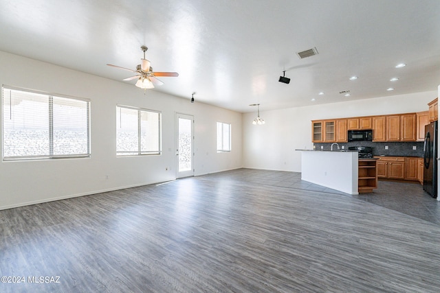 unfurnished living room with ceiling fan with notable chandelier and dark hardwood / wood-style floors