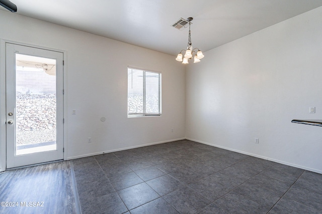 empty room with a chandelier and dark tile patterned floors