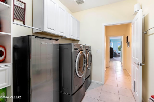 laundry area featuring washing machine and clothes dryer, cabinets, and light tile patterned floors