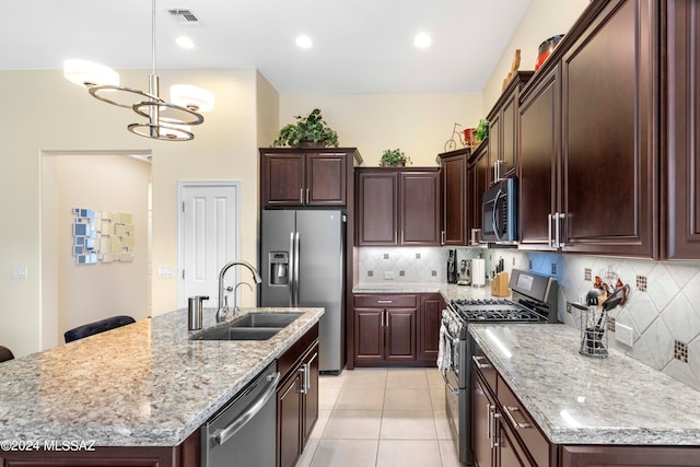 kitchen featuring light tile patterned flooring, sink, light stone countertops, an island with sink, and appliances with stainless steel finishes