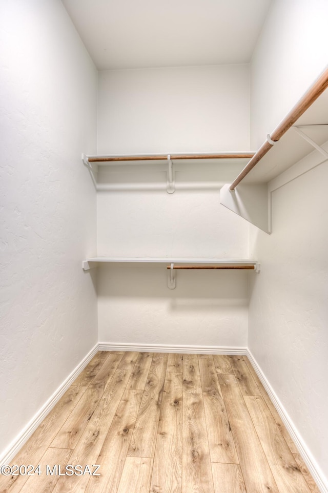 walk in closet with light hardwood / wood-style flooring