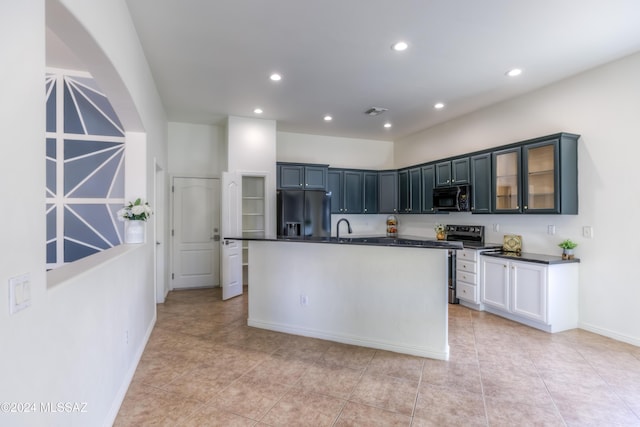 kitchen with sink, a center island with sink, light tile patterned floors, and appliances with stainless steel finishes