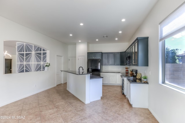 kitchen with light tile patterned flooring, an island with sink, a wealth of natural light, and black appliances