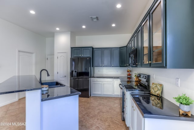 kitchen featuring light tile patterned flooring, sink, a center island with sink, and black appliances