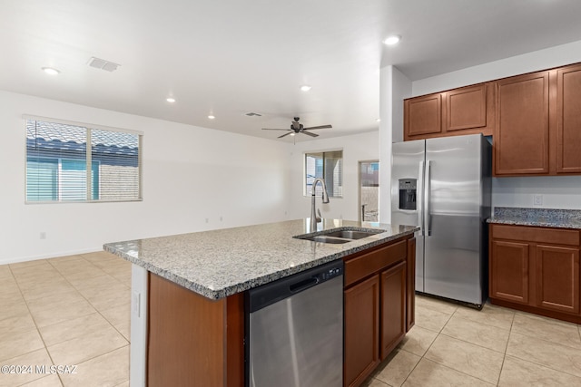 kitchen featuring ceiling fan, sink, a kitchen island with sink, appliances with stainless steel finishes, and light stone countertops