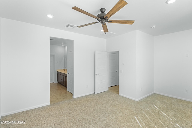 unfurnished bedroom with ceiling fan, light colored carpet, and connected bathroom