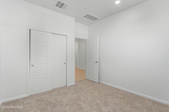 unfurnished bedroom featuring light colored carpet and a closet