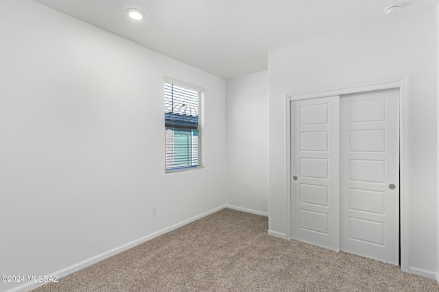 unfurnished bedroom with a closet and light carpet