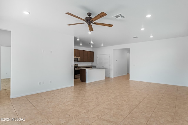 unfurnished living room featuring ceiling fan and sink