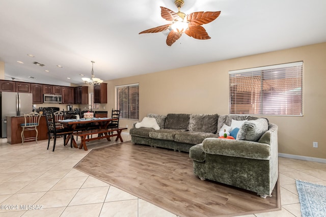 tiled living room with ceiling fan with notable chandelier and vaulted ceiling