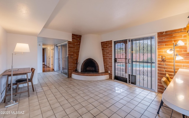 living area with a brick fireplace and light tile patterned flooring