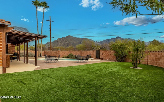 view of yard featuring a mountain view, a fenced backyard, and a patio