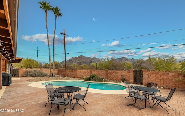 view of pool featuring a patio area, outdoor dining space, a mountain view, and a fenced backyard