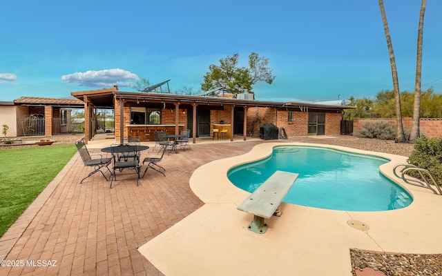 view of swimming pool featuring a fenced in pool, a patio, and a diving board