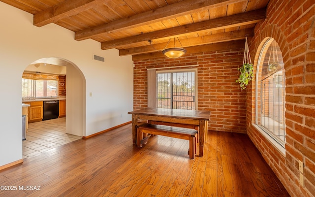 unfurnished dining area featuring wooden ceiling, a healthy amount of sunlight, visible vents, and brick wall