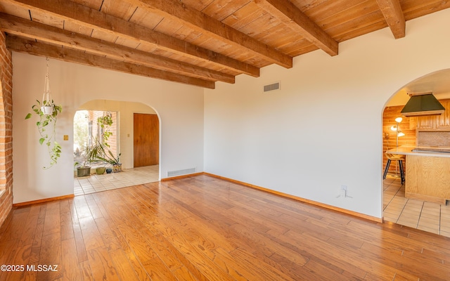 unfurnished room featuring visible vents, wood ceiling, arched walkways, and light wood finished floors