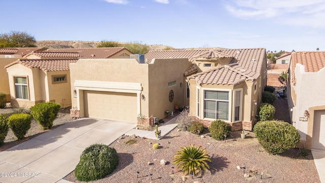 view of front facade with stucco siding, an attached garage, driveway, and a tile roof