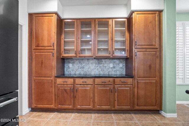 bar with baseboards, freestanding refrigerator, light tile patterned flooring, and tasteful backsplash