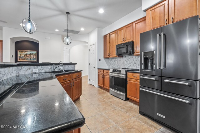 kitchen with dark countertops, a sink, arched walkways, backsplash, and black appliances