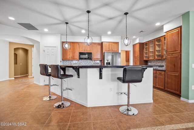 kitchen featuring brown cabinets, dark countertops, black microwave, and stainless steel fridge with ice dispenser