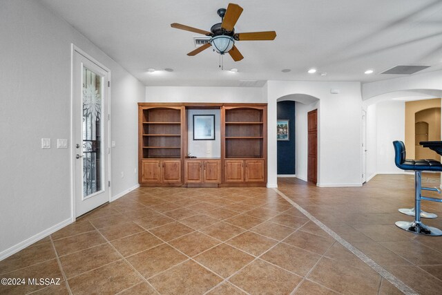 unfurnished living room featuring ceiling fan, arched walkways, tile patterned flooring, baseboards, and recessed lighting