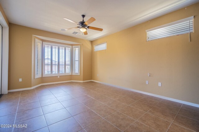 spare room with plenty of natural light, a ceiling fan, tile patterned flooring, and visible vents