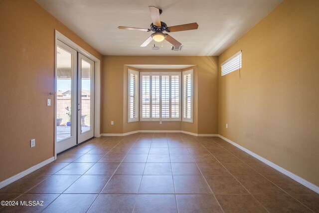 spare room with visible vents, a ceiling fan, baseboards, and dark tile patterned flooring