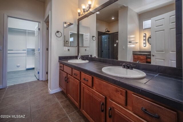 full bathroom featuring double vanity, a sink, tile patterned floors, and a shower stall