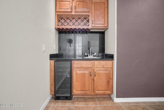 bar with beverage cooler, a sink, baseboards, and wet bar