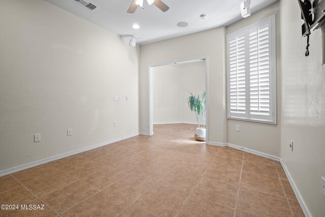 spare room featuring tile patterned flooring, ceiling fan, baseboards, and visible vents