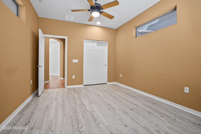 542 W Shadow Wood St, Green Valley, AZ 85614 - unfurnished bedroom with light wood-style floors, arched walkways, a closet, baseboards, and a ceiling fan