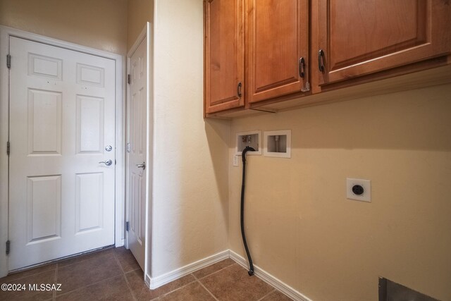 laundry area with hookup for an electric dryer, cabinet space, dark tile patterned flooring, baseboards, and hookup for a washing machine
