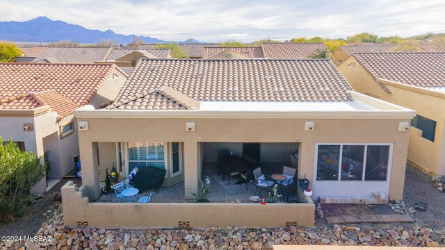 back of house with stucco siding, a patio area, a mountain view, and a tile roof