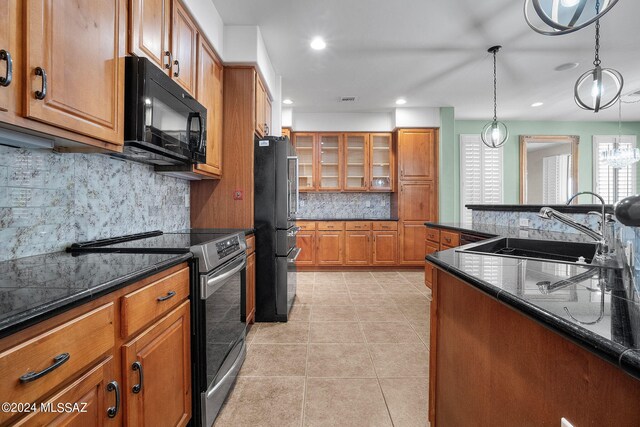 kitchen featuring brown cabinets, a sink, black appliances, and tasteful backsplash