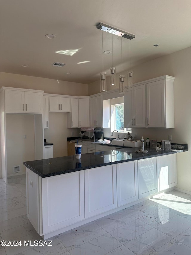 kitchen featuring kitchen peninsula, decorative light fixtures, sink, and white cabinets