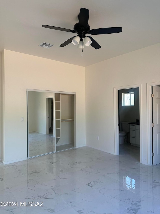 unfurnished bedroom featuring ceiling fan, a closet, ensuite bath, and a walk in closet