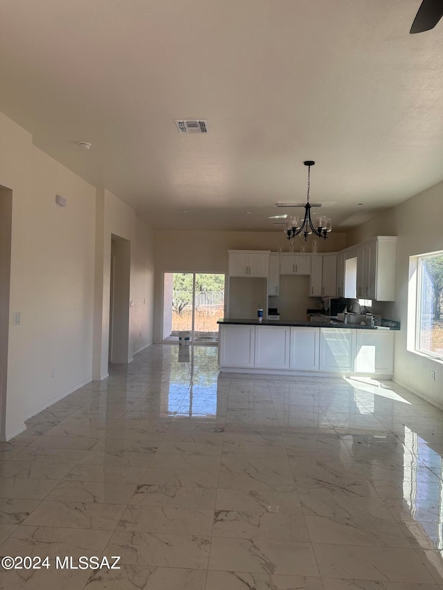 interior space with white cabinets, a notable chandelier, and hanging light fixtures