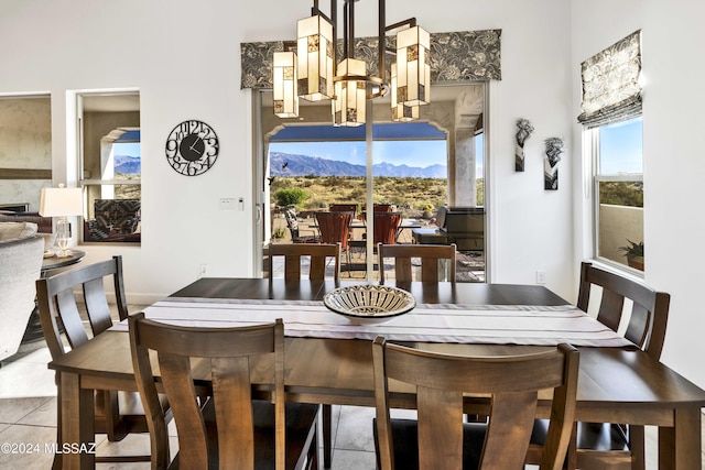 tiled dining space featuring an inviting chandelier, a mountain view, and a towering ceiling