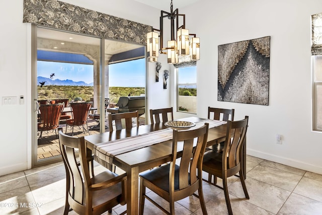 dining space with baseboards, a chandelier, a mountain view, and light tile patterned floors